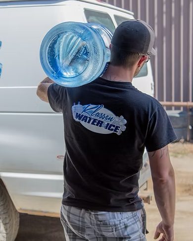 Klassen driver carrying a 5 gallon bottle from the delivery van